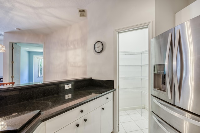 606 SW Treasure Cv, Port Saint Lucie, FL 34986 - kitchen featuring stainless steel fridge, white cabinets, light tile patterned flooring, dark stone counters, and a textured ceiling