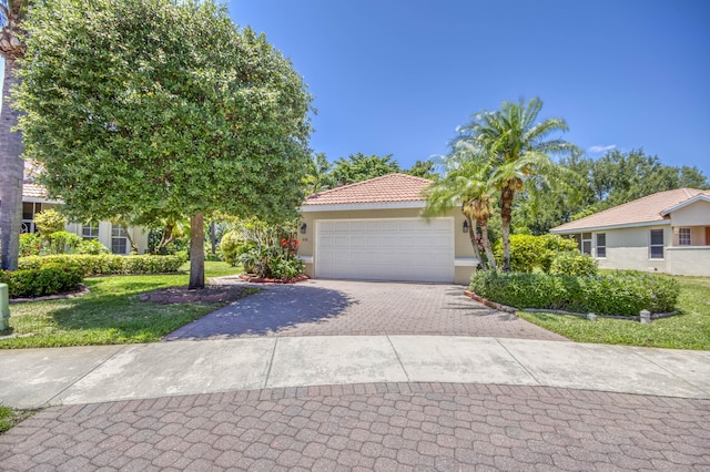 606 SW Treasure Cv, Port Saint Lucie, FL 34986 - view of front facade with stucco siding, driveway, a tile roof, an attached garage, and a front lawn
