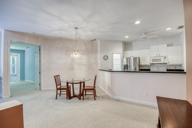 606 SW Treasure Cv, Port Saint Lucie, FL 34986 - kitchen featuring white microwave, stainless steel refrigerator with ice dispenser, stove, dark countertops, and light colored carpet