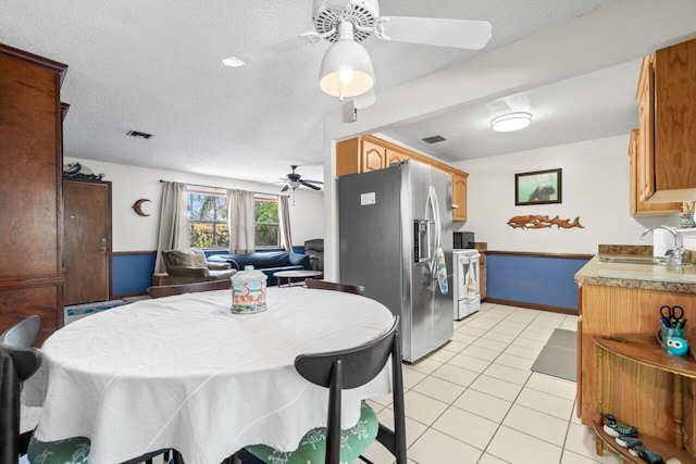 kitchen featuring a sink, light tile patterned flooring, open floor plan, stainless steel fridge, and a ceiling fan