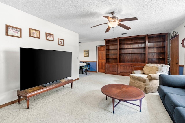 carpeted living room featuring baseboards, ceiling fan, a textured ceiling, and visible vents