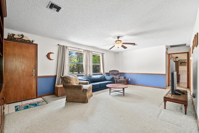 carpeted living room featuring baseboards, a ceiling fan, a textured ceiling, and visible vents