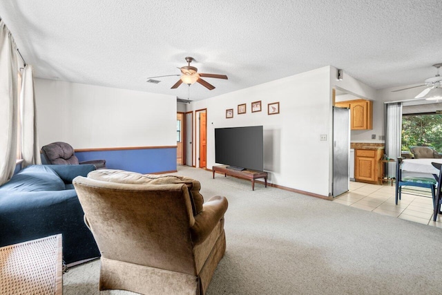 living room featuring light carpet, a textured ceiling, a ceiling fan, baseboards, and visible vents