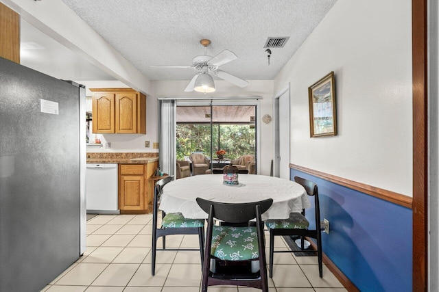 dining space with visible vents, a ceiling fan, a textured ceiling, and light tile patterned floors
