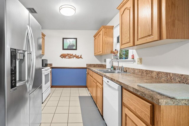 kitchen featuring visible vents, a sink, light tile patterned floors, baseboards, and white appliances