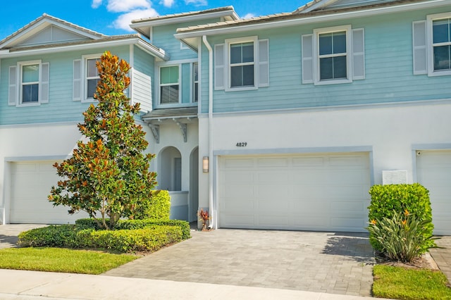 view of front facade with decorative driveway, an attached garage, and stucco siding