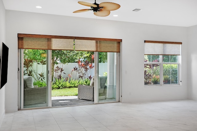 empty room featuring visible vents, a ceiling fan, marble finish floor, and a wealth of natural light