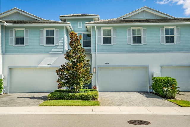 view of property featuring stucco siding, decorative driveway, and a garage