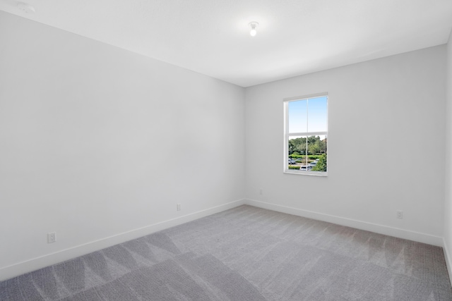 unfurnished room featuring baseboards and light colored carpet
