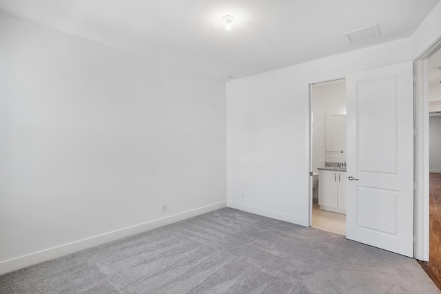 unfurnished bedroom with a walk in closet, attic access, visible vents, light colored carpet, and baseboards
