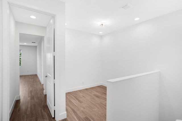 hallway featuring baseboards, recessed lighting, wood finished floors, and visible vents