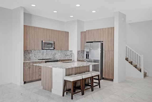 kitchen featuring light stone countertops, a breakfast bar, modern cabinets, a sink, and appliances with stainless steel finishes