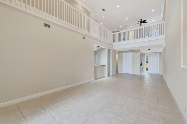 unfurnished living room with ceiling fan, a high ceiling, baseboards, light tile patterned floors, and visible vents