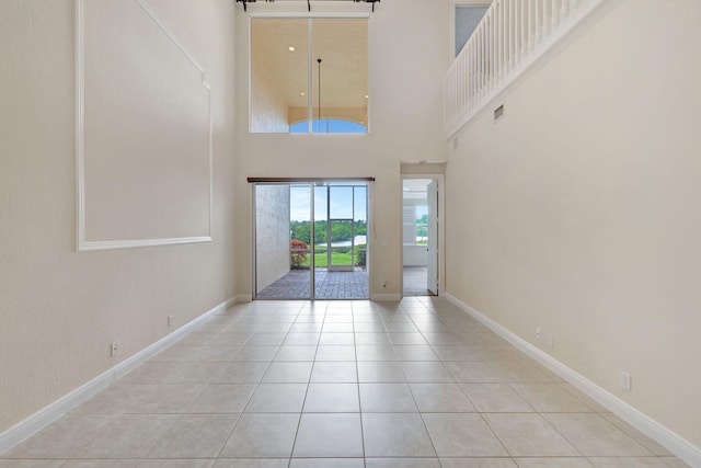 tiled foyer featuring baseboards and a towering ceiling