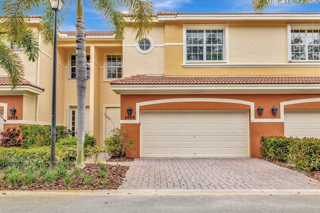 view of front of property with decorative driveway, a garage, stucco siding, and a tile roof