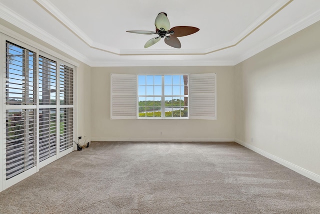 spare room with crown molding, a raised ceiling, a ceiling fan, and carpet floors