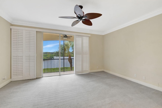 carpeted spare room with crown molding, baseboards, and ceiling fan