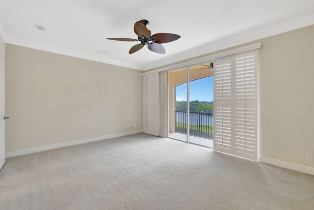 spare room with crown molding, baseboards, ceiling fan, a water view, and carpet