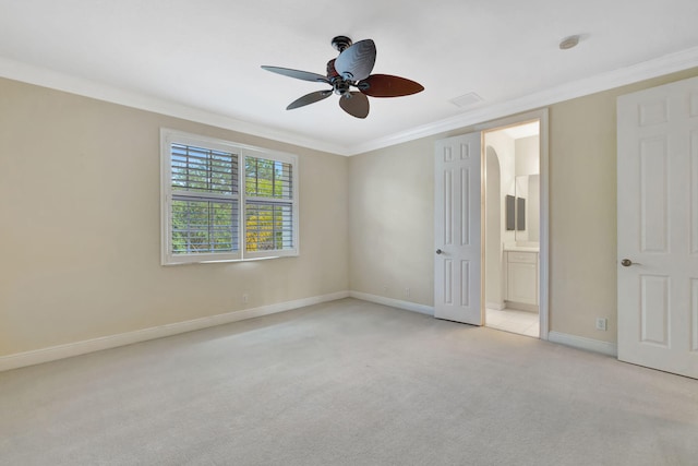 unfurnished bedroom with crown molding, baseboards, ensuite bathroom, and light carpet