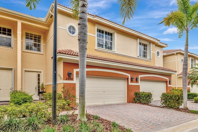 view of front of home featuring stucco siding, an attached garage, decorative driveway, and a tiled roof