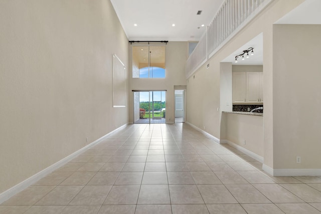 interior space featuring light tile patterned floors, baseboards, a high ceiling, and recessed lighting