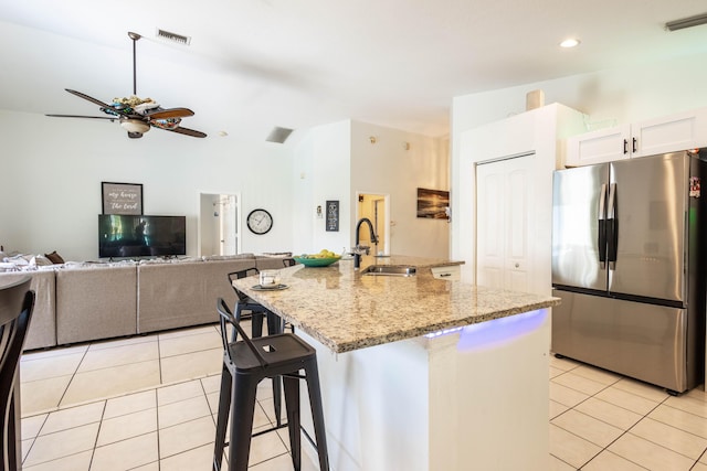 kitchen featuring visible vents, freestanding refrigerator, ceiling fan, a sink, and light tile patterned floors