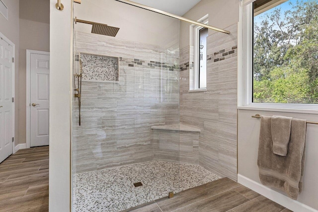 full bathroom with baseboards, visible vents, tiled shower, and wood finished floors