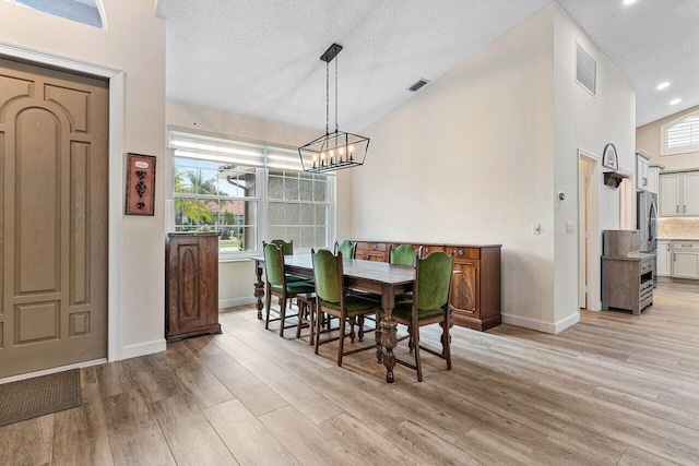 dining area with plenty of natural light, a notable chandelier, light wood-type flooring, and visible vents
