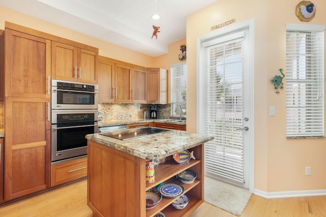 kitchen featuring open shelves, a sink, cooktop, decorative backsplash, and light stone counters
