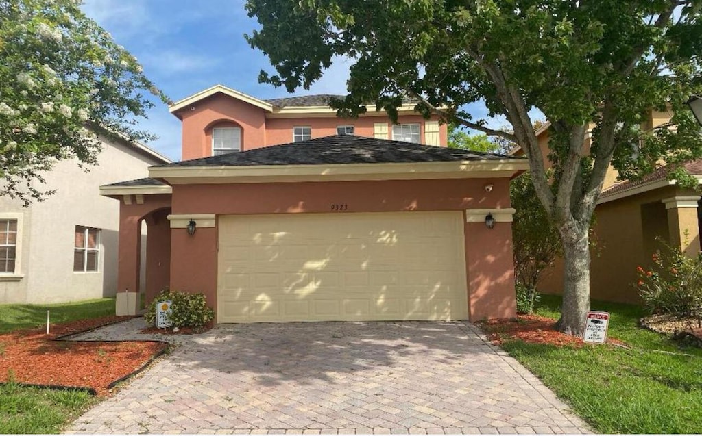 view of front facade with stucco siding, an attached garage, and driveway