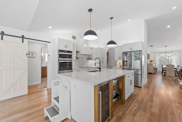 kitchen featuring a sink, light wood-style flooring, stainless steel appliances, and beverage cooler