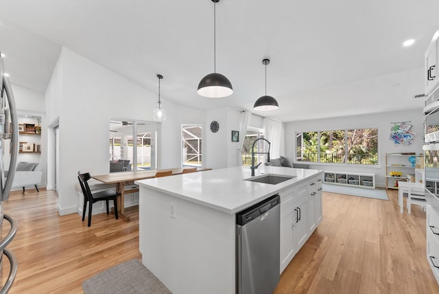 kitchen with stainless steel dishwasher, a sink, light wood-style flooring, and a center island with sink