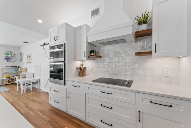 kitchen with double oven, open shelves, black electric stovetop, and premium range hood