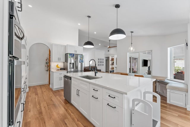 kitchen featuring a sink, appliances with stainless steel finishes, light wood-type flooring, and an island with sink