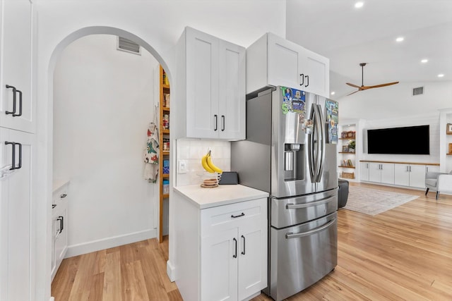 kitchen featuring ceiling fan, stainless steel refrigerator with ice dispenser, visible vents, light wood-type flooring, and open floor plan