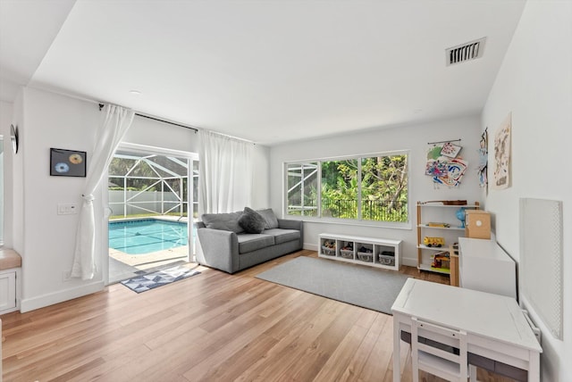 living area with light wood-type flooring, baseboards, a sunroom, and visible vents