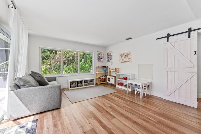 interior space with baseboards, visible vents, a barn door, and wood finished floors