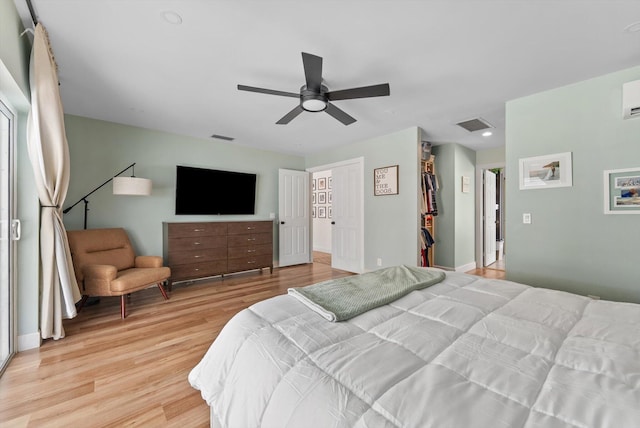 bedroom featuring a ceiling fan, visible vents, a spacious closet, and light wood finished floors