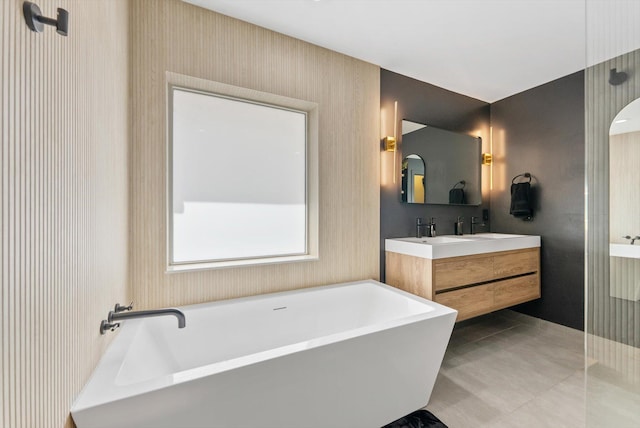 bathroom featuring double vanity, wallpapered walls, a freestanding bath, and tile patterned flooring