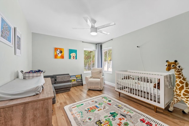 bedroom featuring a ceiling fan, a crib, and wood finished floors