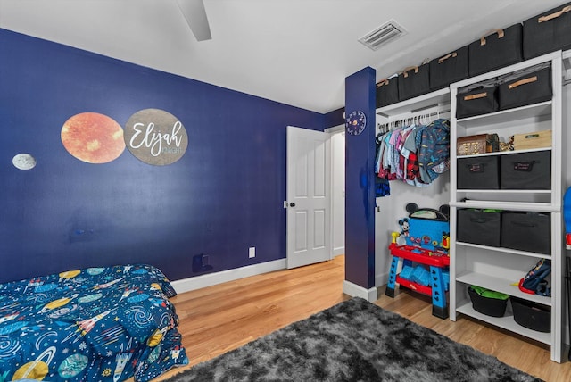 bedroom with visible vents, baseboards, and wood finished floors