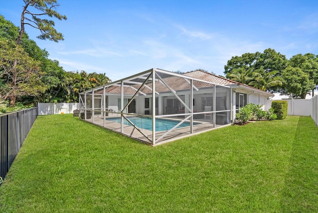 rear view of house with a lawn, a fenced backyard, glass enclosure, and a fenced in pool