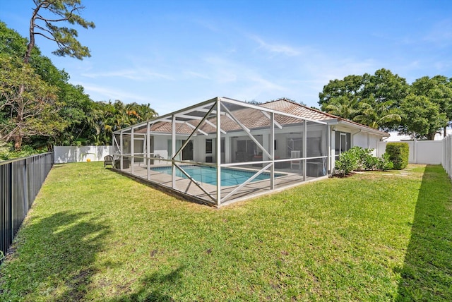 rear view of property with a fenced backyard, a fenced in pool, a lawn, and a lanai