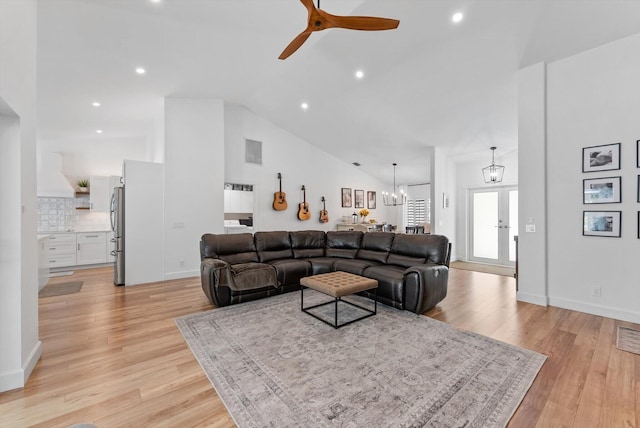 living room with light wood-style floors, high vaulted ceiling, ceiling fan with notable chandelier, and recessed lighting