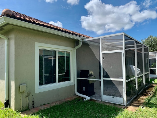 view of side of home with a lanai, a tile roof, and stucco siding