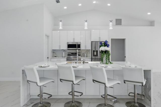 2449 SE Rock Springs Dr, Port Saint Lucie, FL 34952 - kitchen with appliances with stainless steel finishes, light marble finish flooring, white cabinets, hanging light fixtures, and a kitchen island with sink