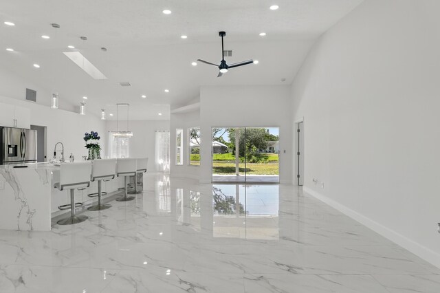 2449 SE Rock Springs Dr, Port Saint Lucie, FL 34952 - living room featuring high vaulted ceiling, light marble finish flooring, recessed lighting, a skylight, and baseboards