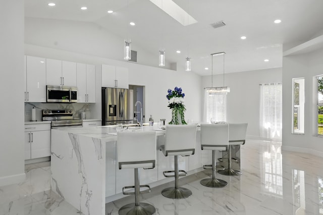 2449 SE Rock Springs Dr, Port Saint Lucie, FL 34952 - kitchen featuring stainless steel appliances, light marble finish floors, recessed lighting, white cabinets, and a spacious island