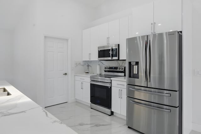 2449 SE Rock Springs Dr, Port Saint Lucie, FL 34952 - kitchen featuring appliances with stainless steel finishes, light marble finish floors, white cabinets, decorative backsplash, and light stone countertops