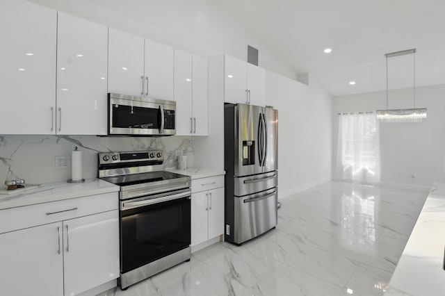 2449 SE Rock Springs Dr, Port Saint Lucie, FL 34952 - kitchen featuring appliances with stainless steel finishes, light marble finish flooring, white cabinetry, vaulted ceiling, and hanging light fixtures